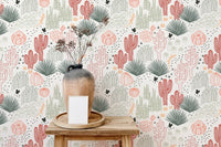 Tabletop decor against a background of pink and green succulent wallpaper.