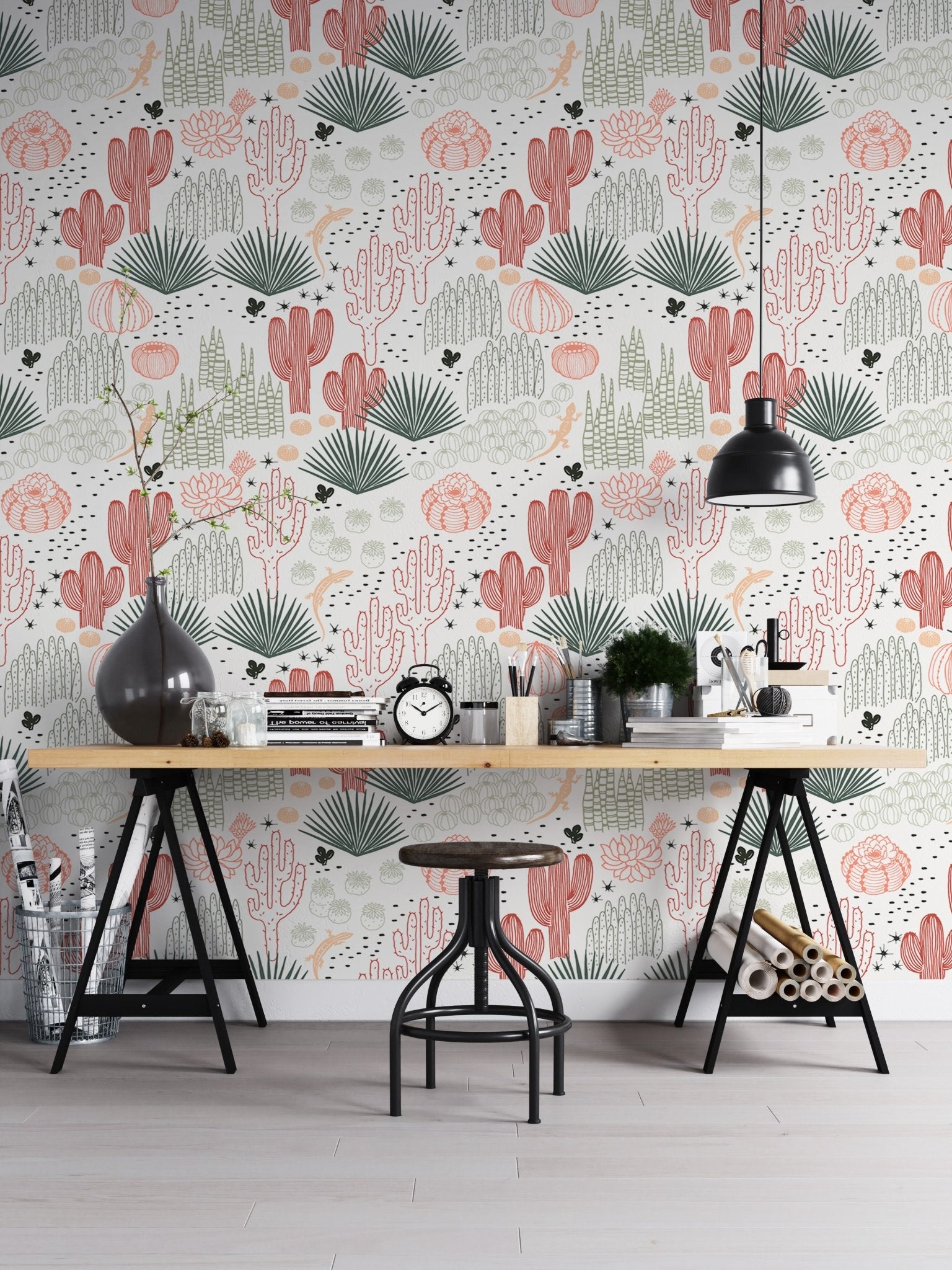 Succulent wallpaper behind a wooden desk and black industrial lamps in a workspace.