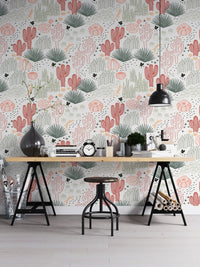 Succulent wallpaper behind a wooden desk and black industrial lamps in a workspace.