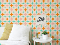 Geometric star wall mural in bedroom behind bed and white table.