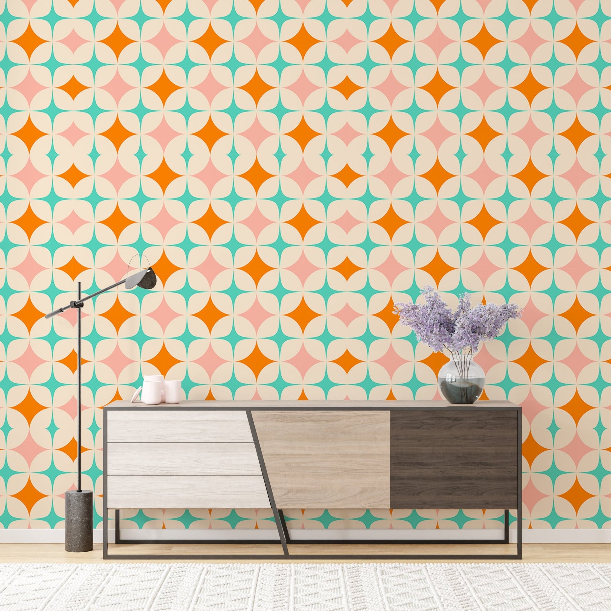 Multi-colored diamond wall mural behind a modern wooden cabinet and purple flowers.