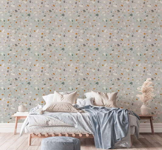 Terrazzo pattern wallpaper behind a large bed with blue and grey cushions.