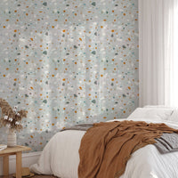 Bedroom wallpaper with terrazzo chips in orange and teal behind a brown blanket.