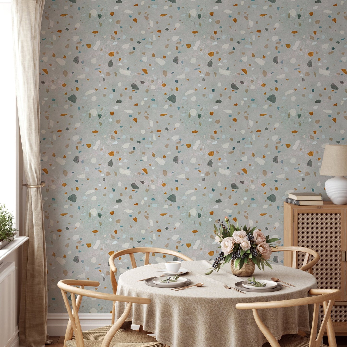Round dining table with chairs set against a classic terrazzo wallpaper.