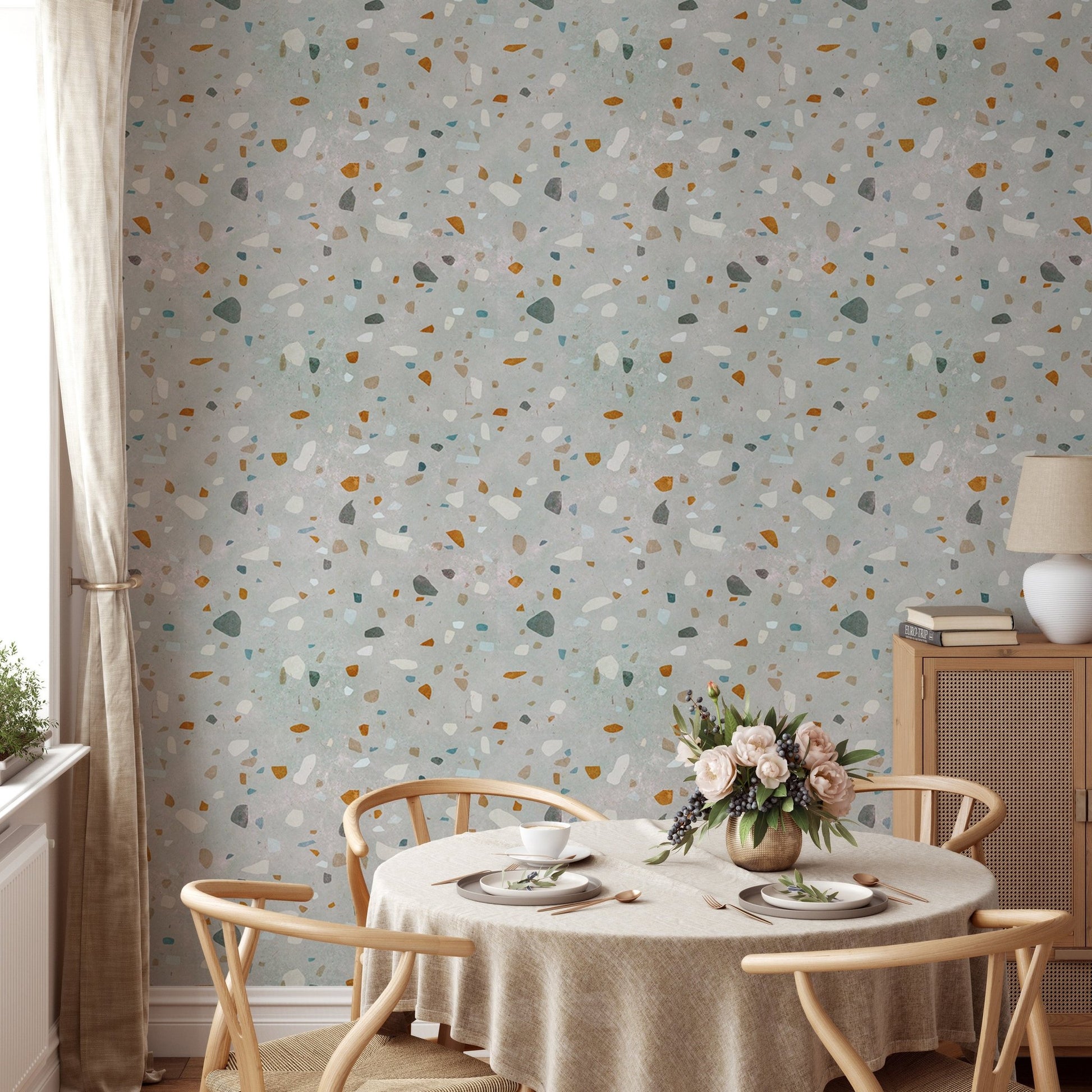 Round dining table with chairs set against a classic terrazzo wallpaper.