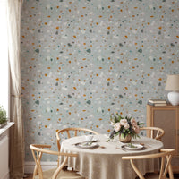 Round dining table with chairs set against a classic terrazzo wallpaper.