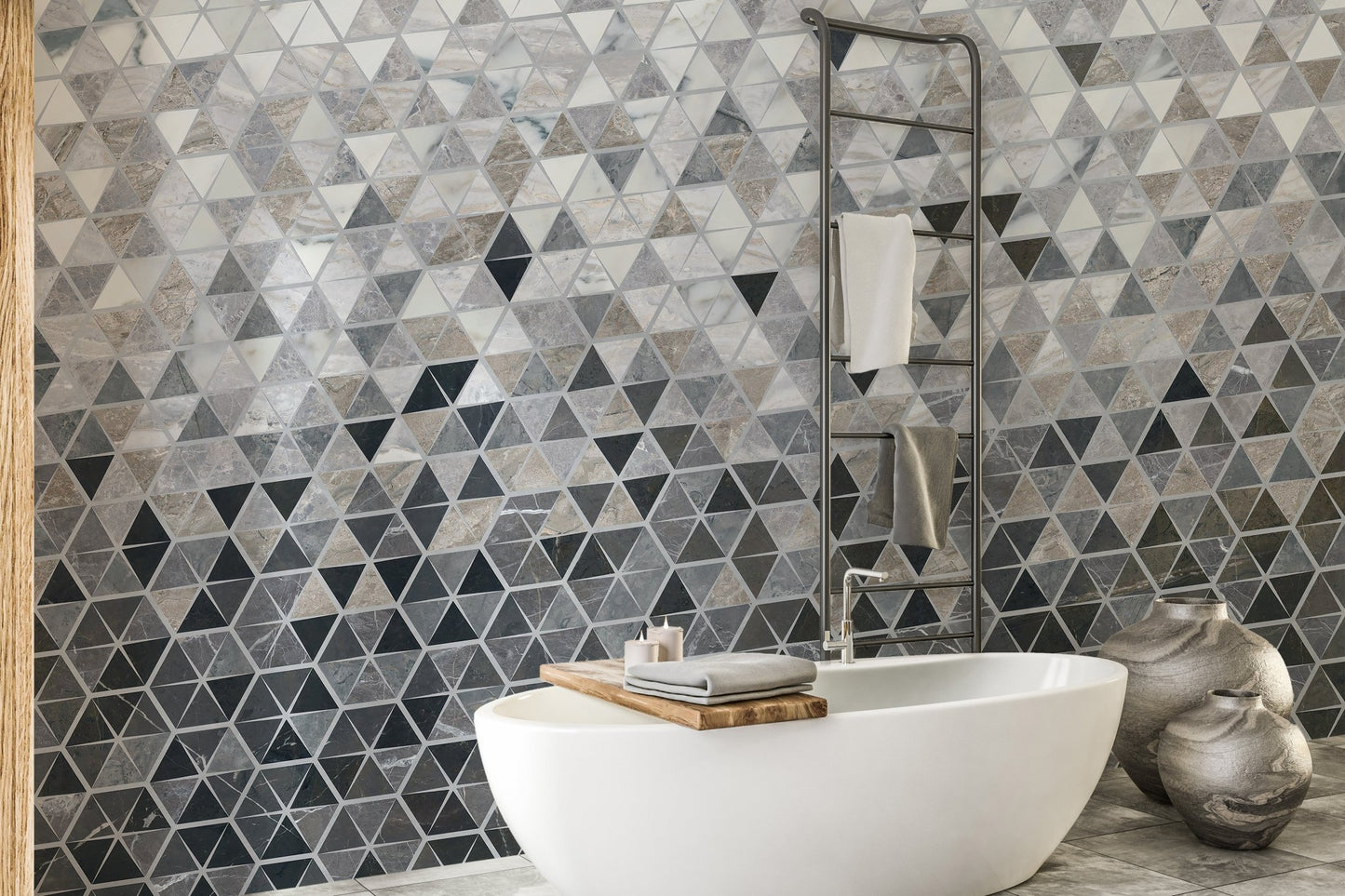 Blue and grey tiles wall mural in a bathroom behind a white soaking tub.