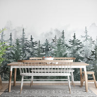 Green pine tree wall mural behind a long wooden dining table and white bench.