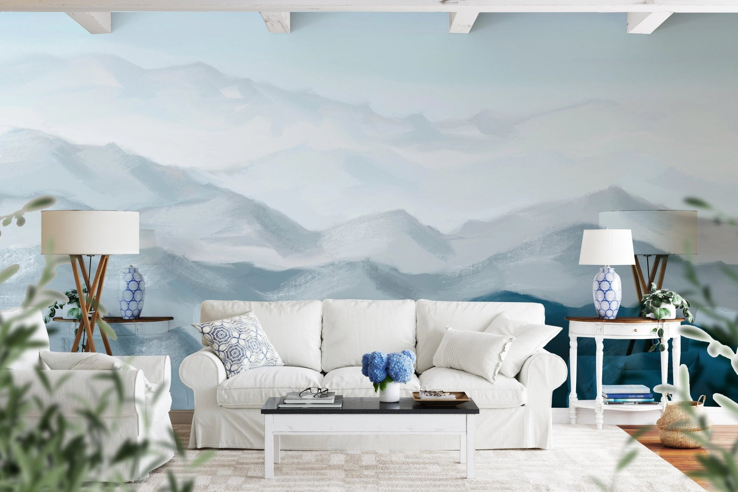 Blue ombre mountain wall mural behind a white fabric sofa and green plants