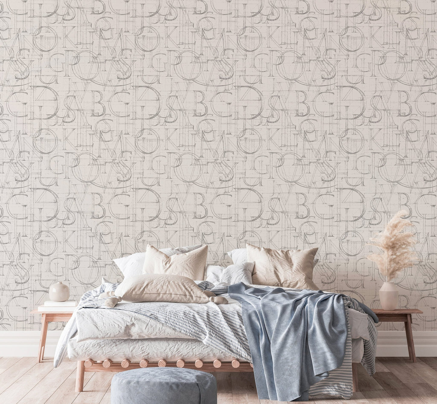 Roman letter wallpaper in a bedroom featuring blue bedding and wooden side tables.