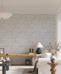 Roman alphabet wallpaper in a bright living area with a white sofa and wooden desk.