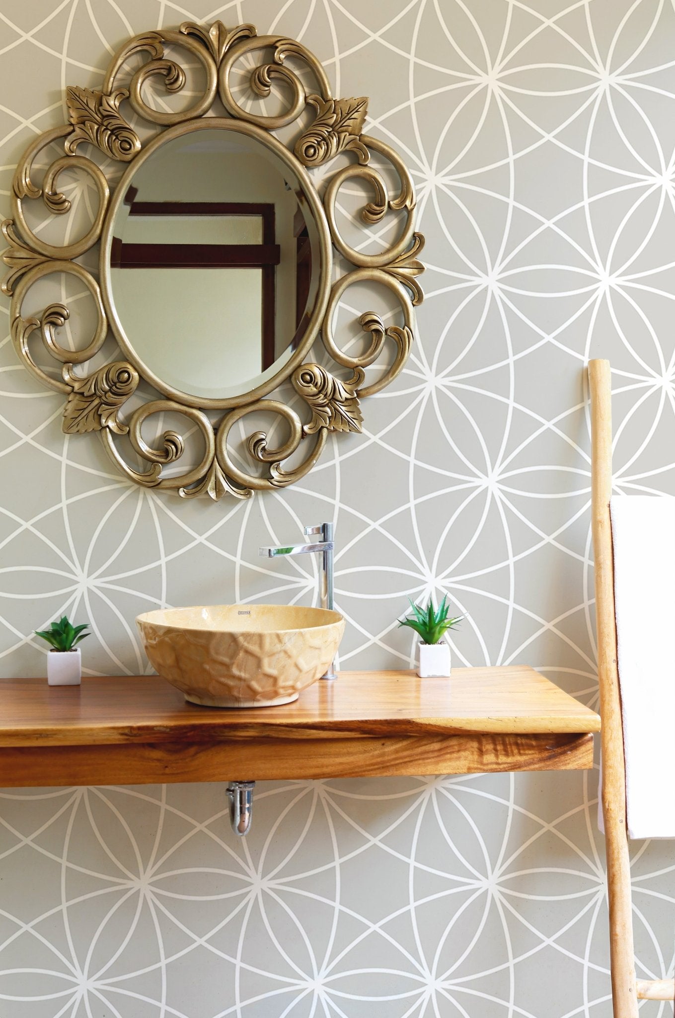 Modern geometric wallpaper in a bathroom with a round mirror and wood sink.