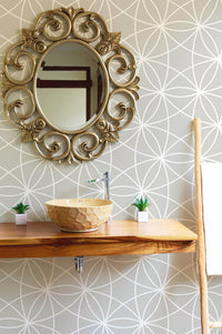 Modern geometric wallpaper in a bathroom with a round mirror and wood sink.