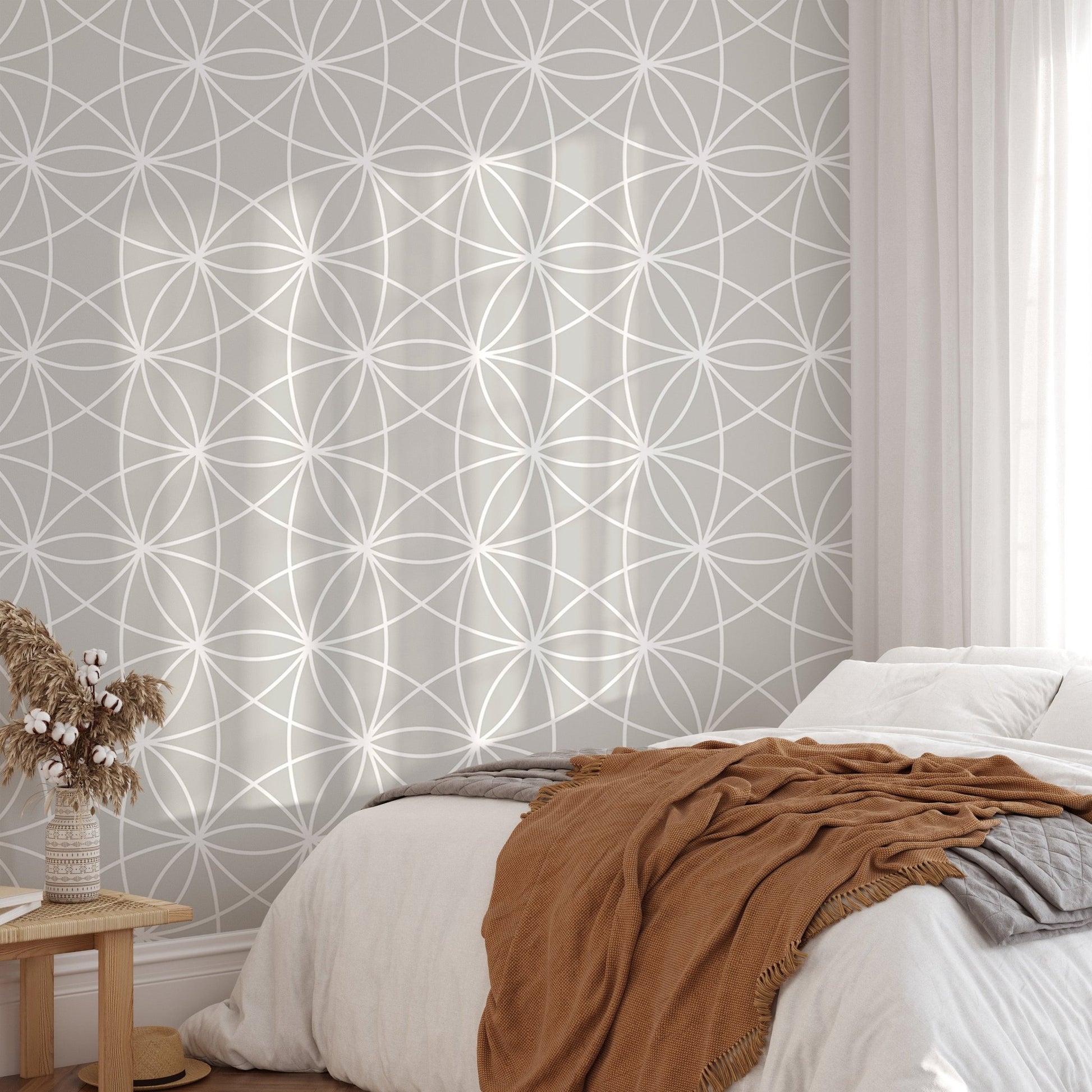 Neutral tone geometric wallpaper mural behind a bed with brown throw pillows.