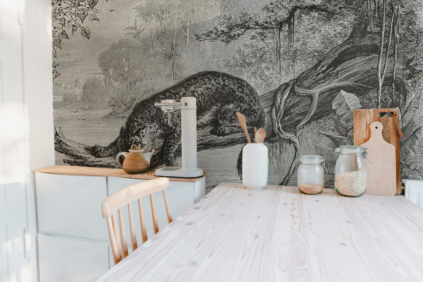 Minimalist dining room with a monochrome leopard wall mural and light wood chairs.