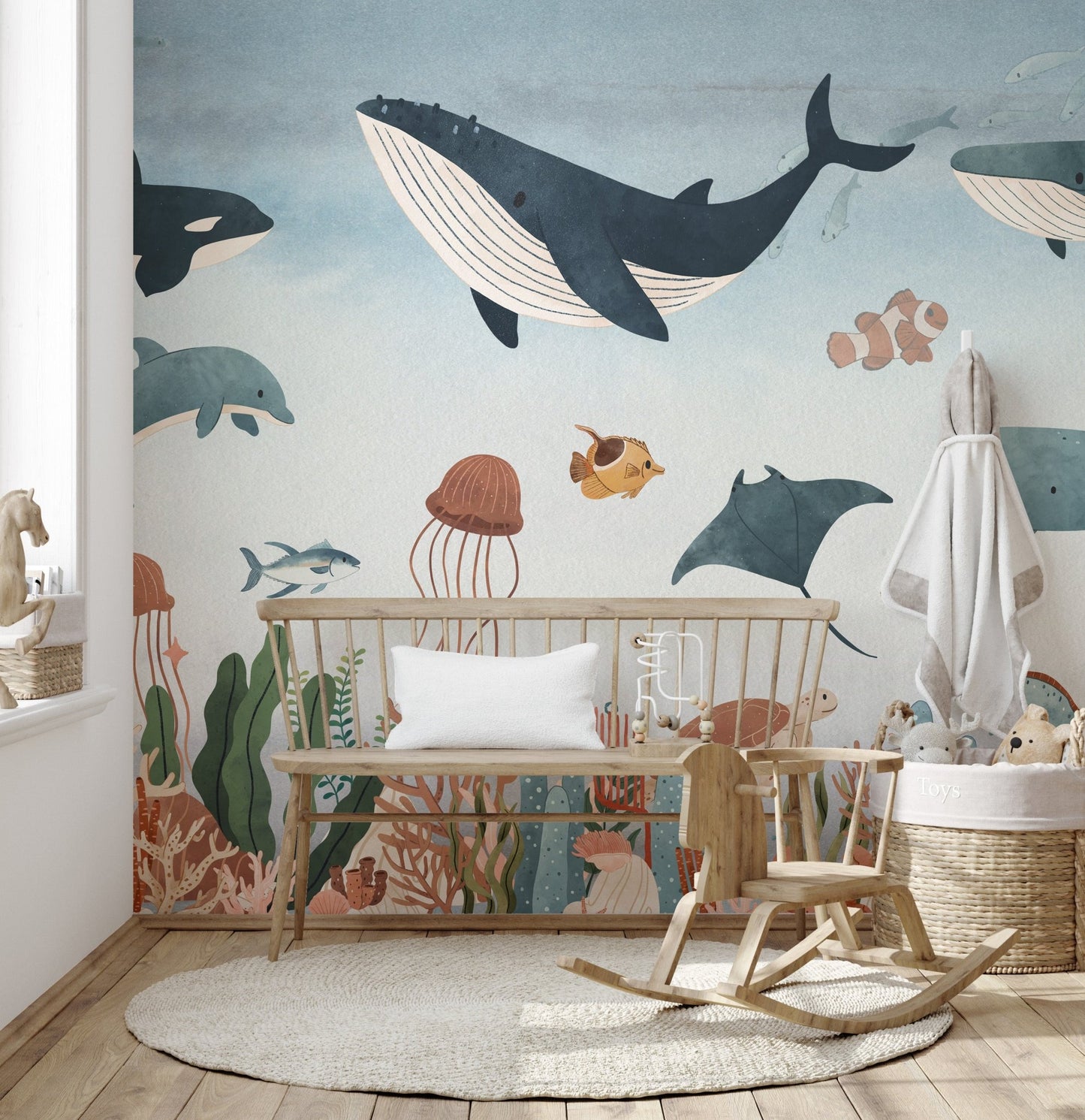 Whale and stingray underwater wall mural behind a wooden bench and rocking horse in nursery.