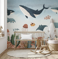 Whale and stingray underwater wall mural behind a wooden bench and rocking horse in nursery.