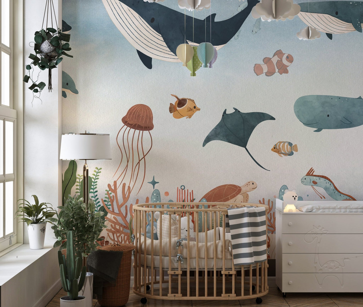 Underwater animal wall mural in a nursery with a wooden crib and indoor plants.