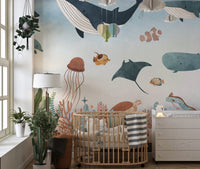 Underwater animal wall mural in a nursery with a wooden crib and indoor plants.