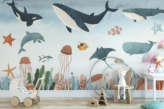 Hand-drawn underwater wall mural in a bright nursery with a white bunny on chair.