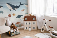 Monochrome Marine life wall mural in a play area with a dollhouse and tricycle.