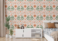 Green snake and orange sun wallpaper in a bedroom behind a white cabinet and bed.