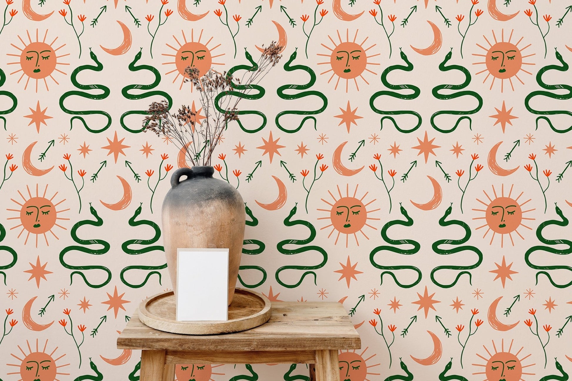 Moon and sun Boho wallpaper with snakes design behind wooden table and vase.