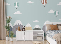 Kids' bedroom with mountain wall mural and white storage cabinets.