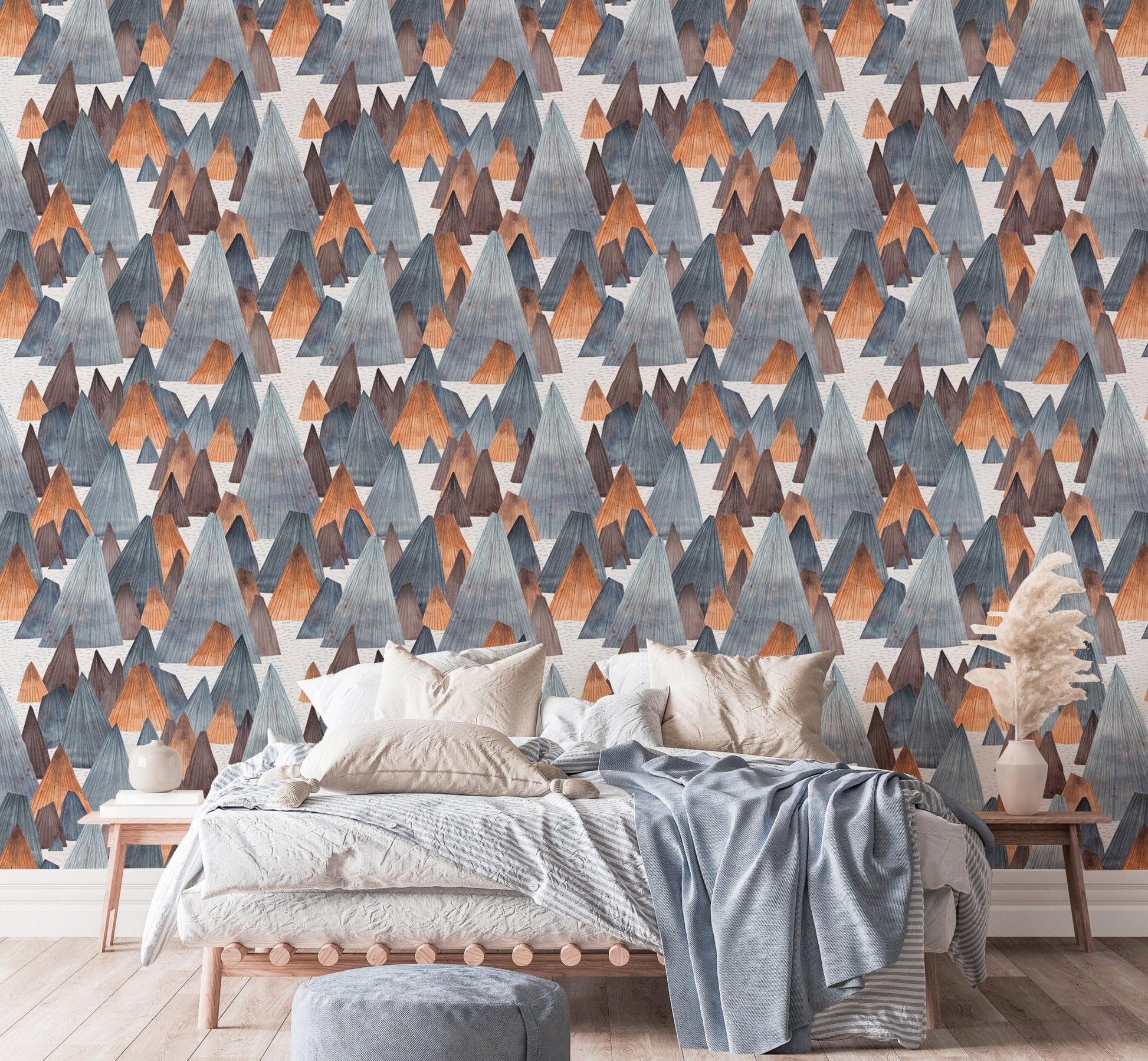 Modern mountain landscape wallpaper behind bed with blue linens.
