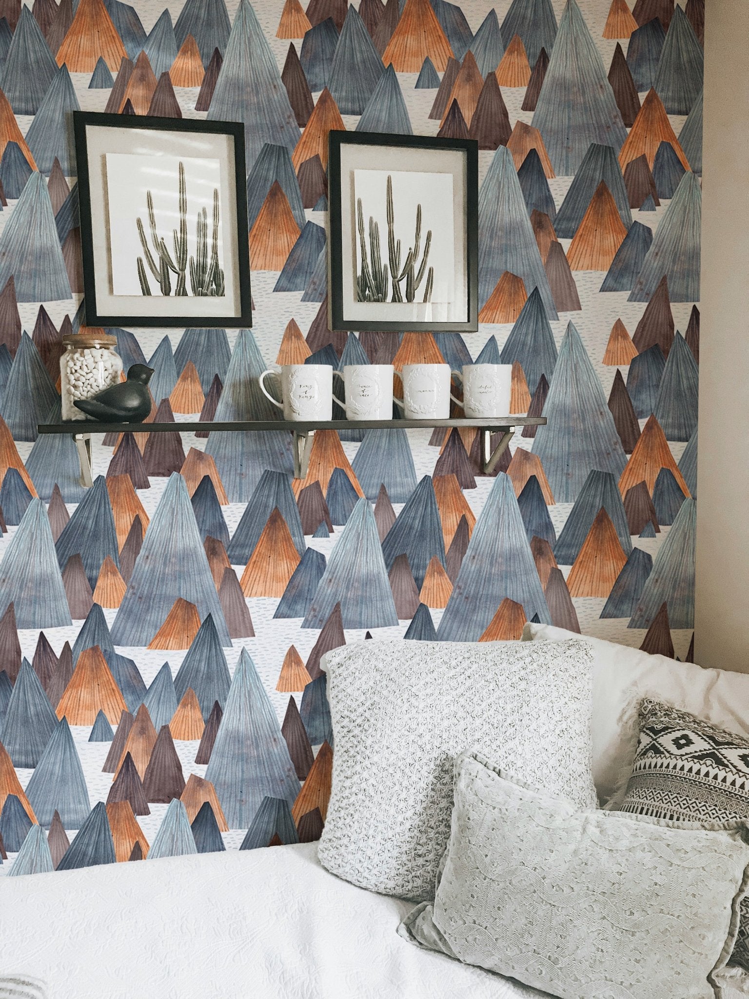 Minimalist mountain wallpaper with black frames and white bedding.