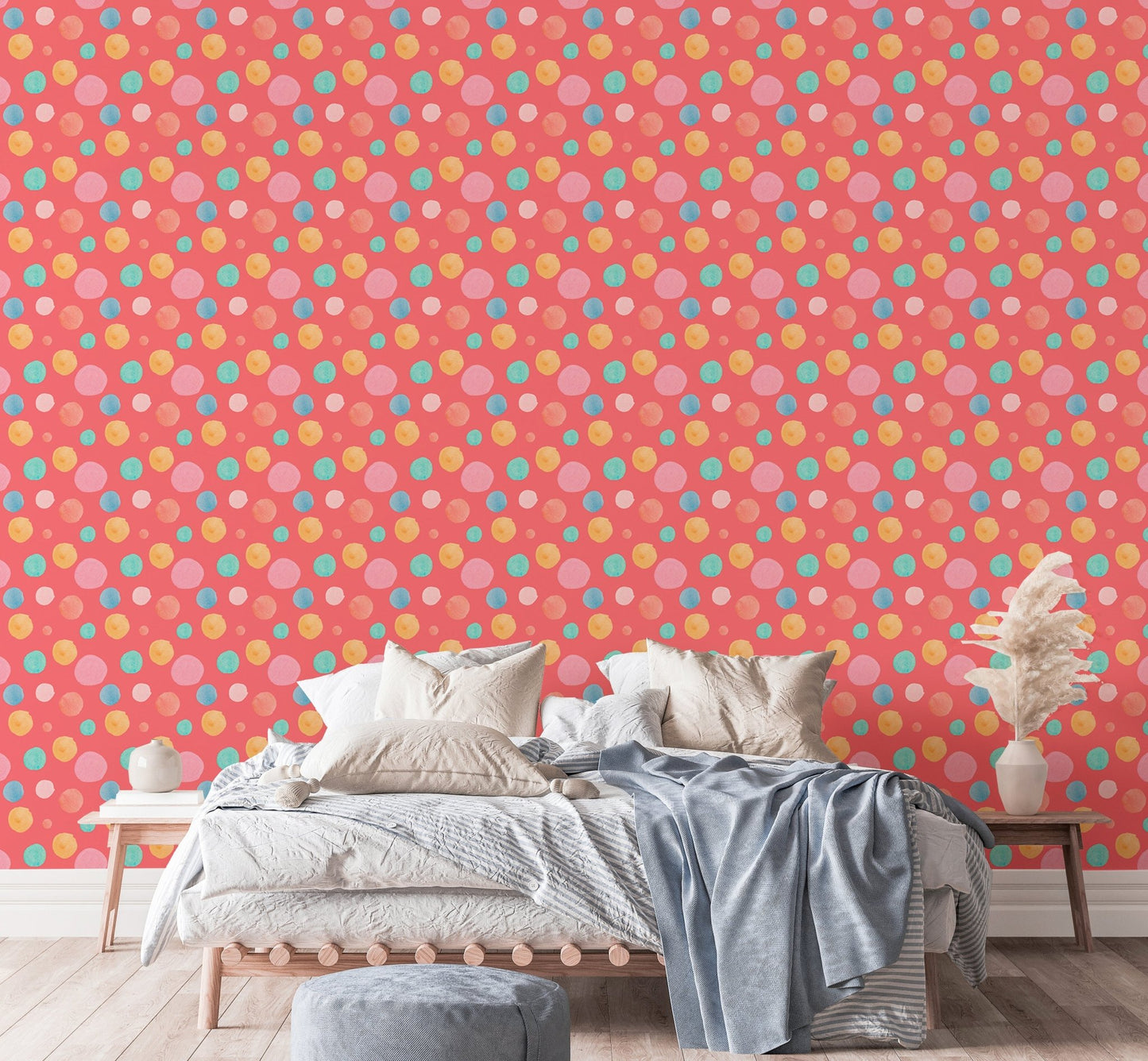 Pink wallpaper with blue and yellow dots behind a bed with grey linens.