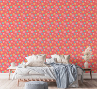 Pink wallpaper with blue and yellow dots behind a bed with grey linens.