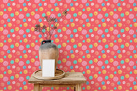 Multicolor wallpaper with round shapes behind a small wooden side table.