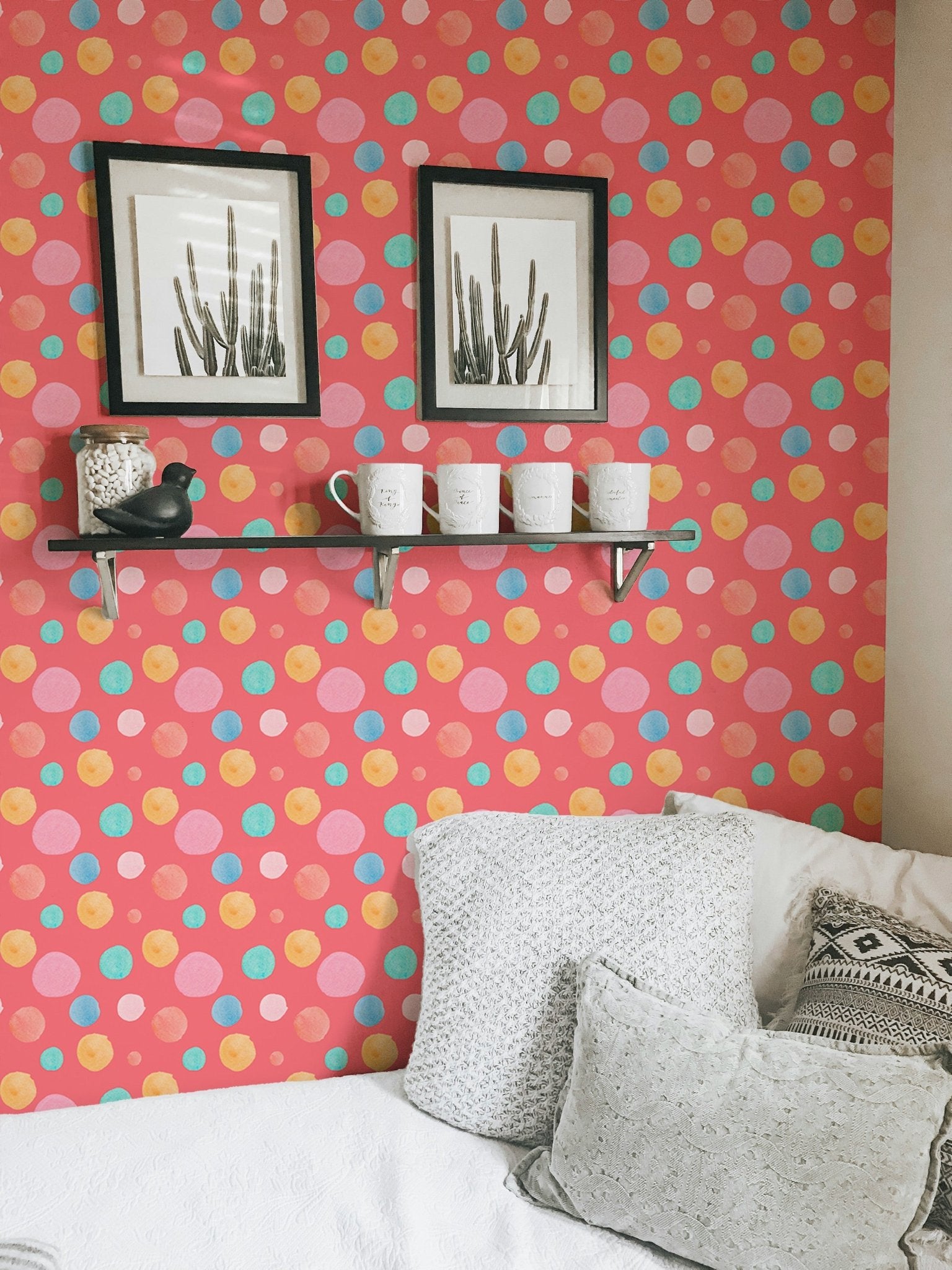 Polka dot wallpaper displayed with white pillows and wooden shelving.