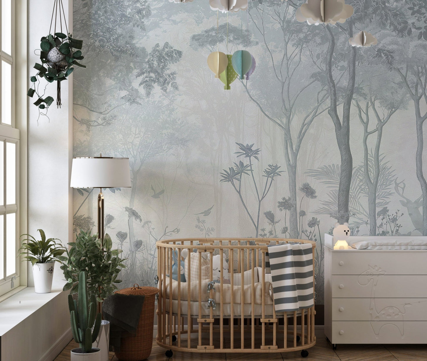 Grey and blue forest wall mural in a nursery next to a light wood crib.