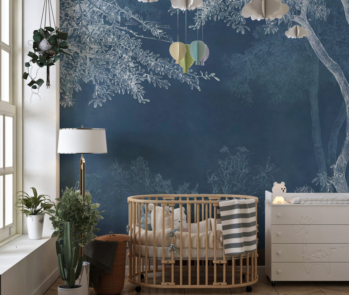 Indigo forest wall mural behind a wooden crib in a nursery with natural light.