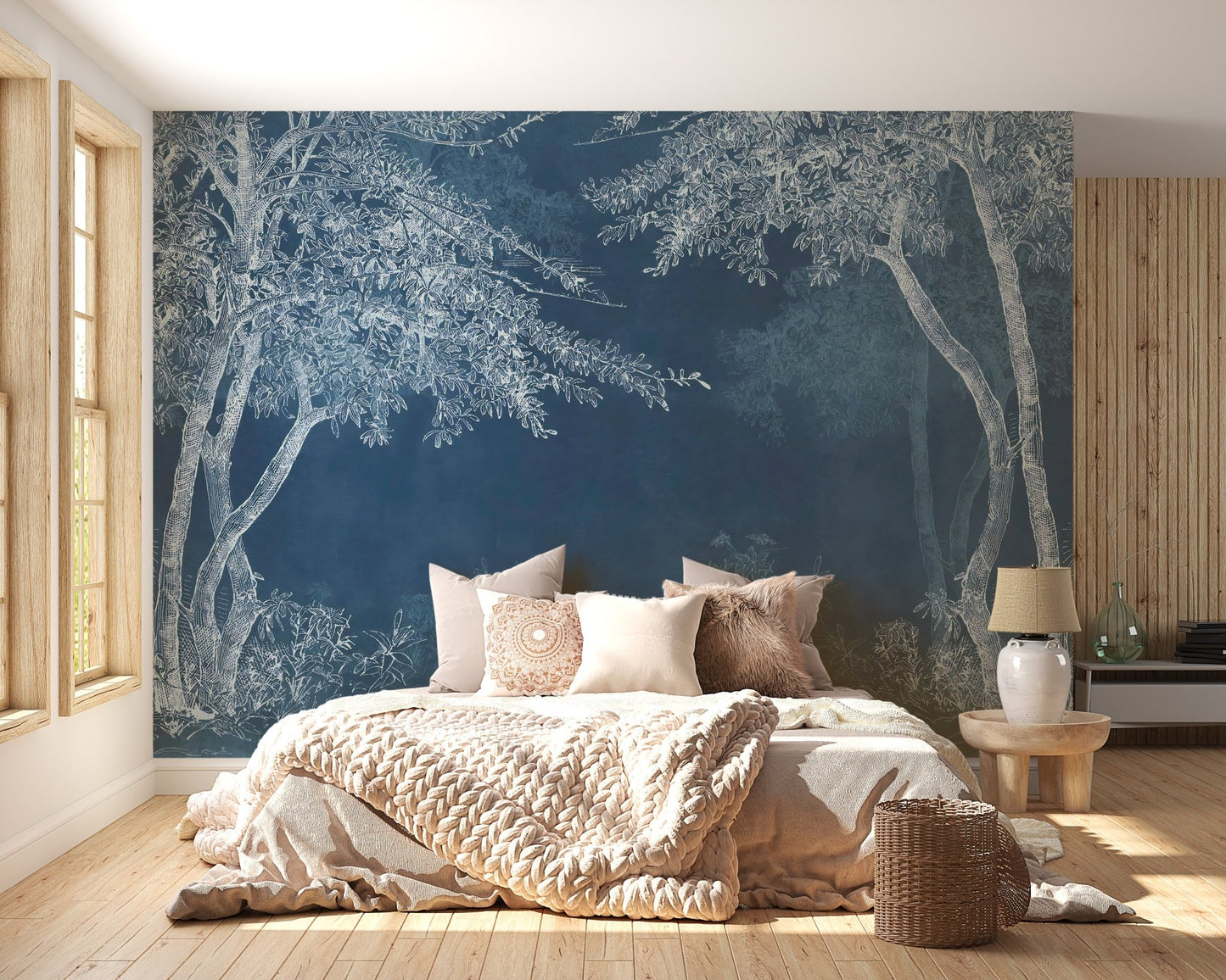 Indigo forest wall mural in a bright bedroom with beige linens and a side table.
