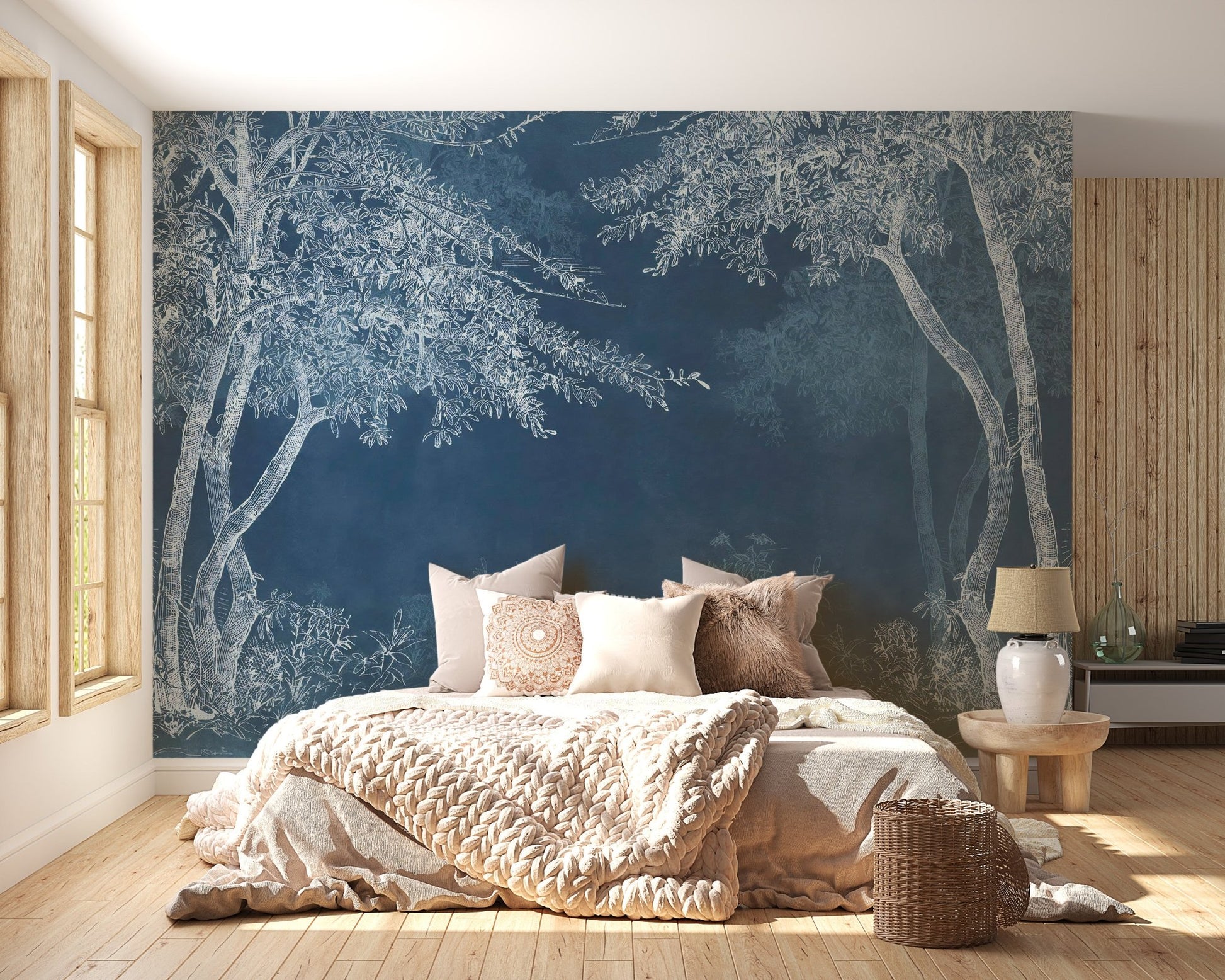 Indigo forest wall mural in a bright bedroom with beige linens and a side table.