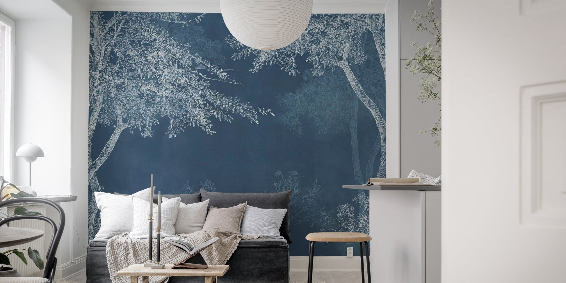 Blue wilderness landscape wall mural in a minimalist living room with a black sofa.