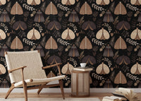 Dark floral wallpaper with insect motifs behind a wooden armchair and table in reading area.