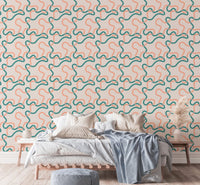 Abstract line wallpaper behind a white bed with brown and blue accent pillows.