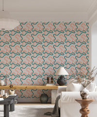 Wallpaper with teal and peach line squiggles behind a white sideboard and indoor plants.