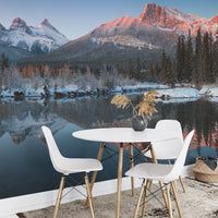 Small white dining area against a mountain and pine forest wall mural.