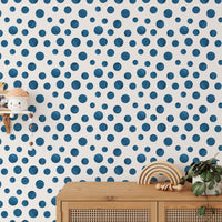 Navy Blue Indigo Watercolor Polka Dots Wallpaper behind a wooden sideboard and plants.