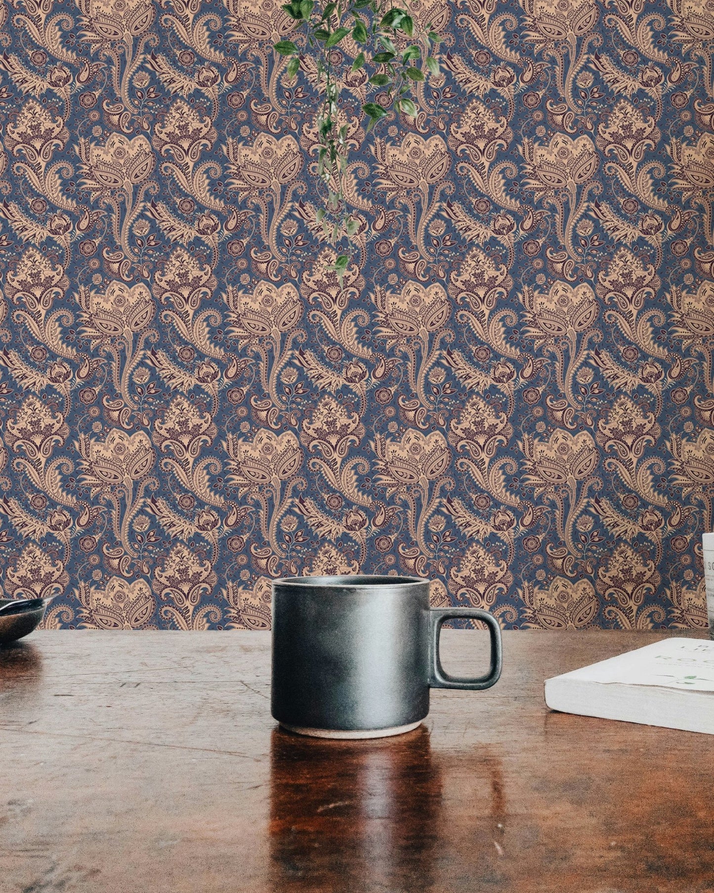 Textured floral wallpaper behind wooden table with black ceramic mug.