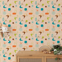 Old vintage style atomic mid century wall mural behind a light wood cabinet and plants.