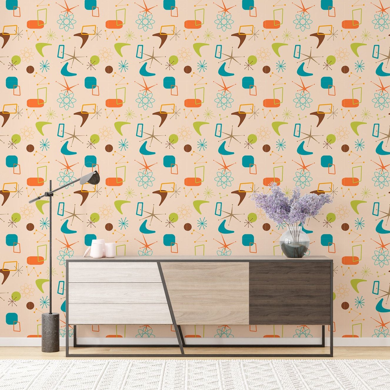 Atomic mid century mural on a wall behind a modern sideboard with a floor lamp.