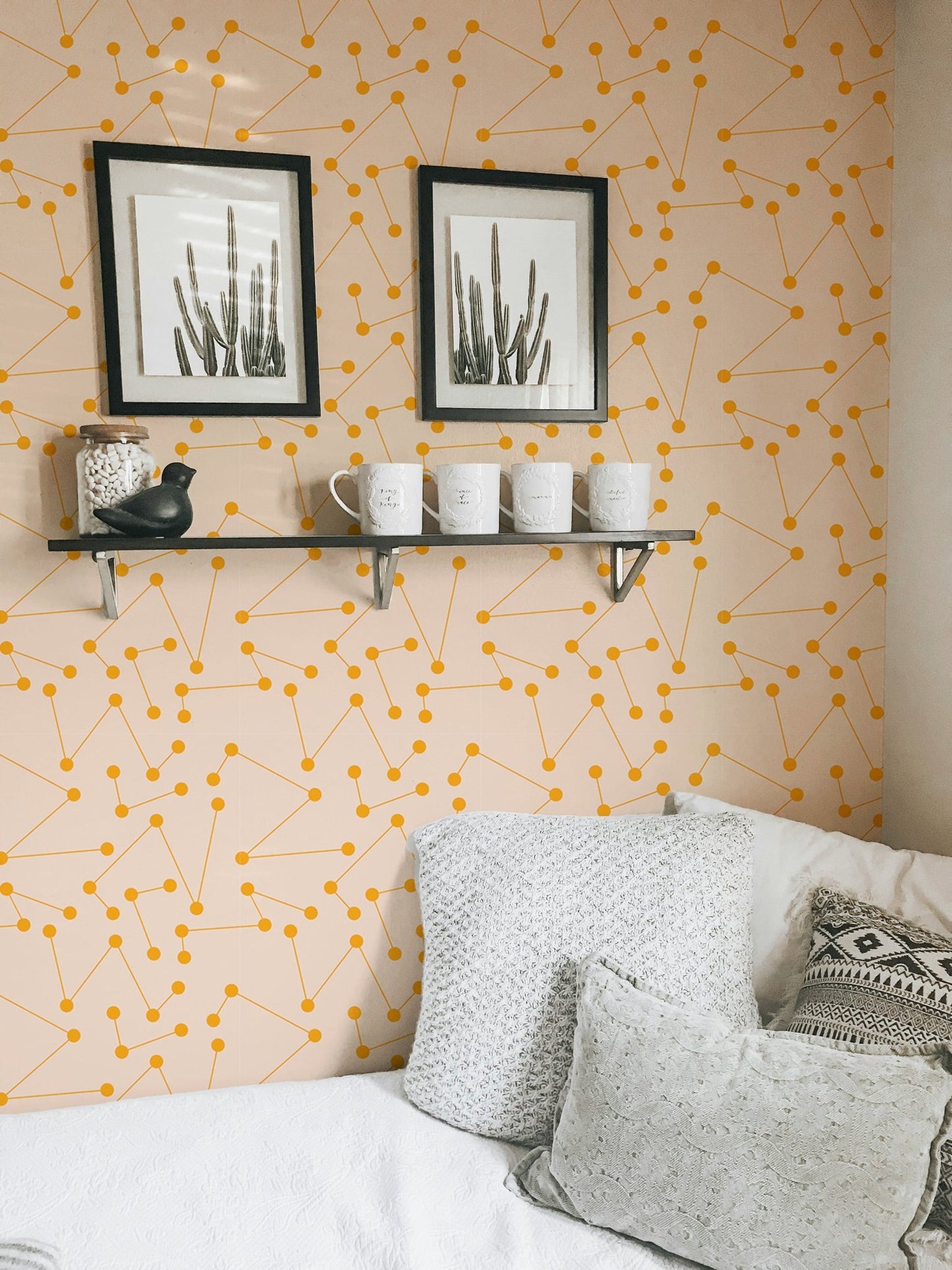 Geometric wall mural in a bedroom featuring white bedding and grey pillows.