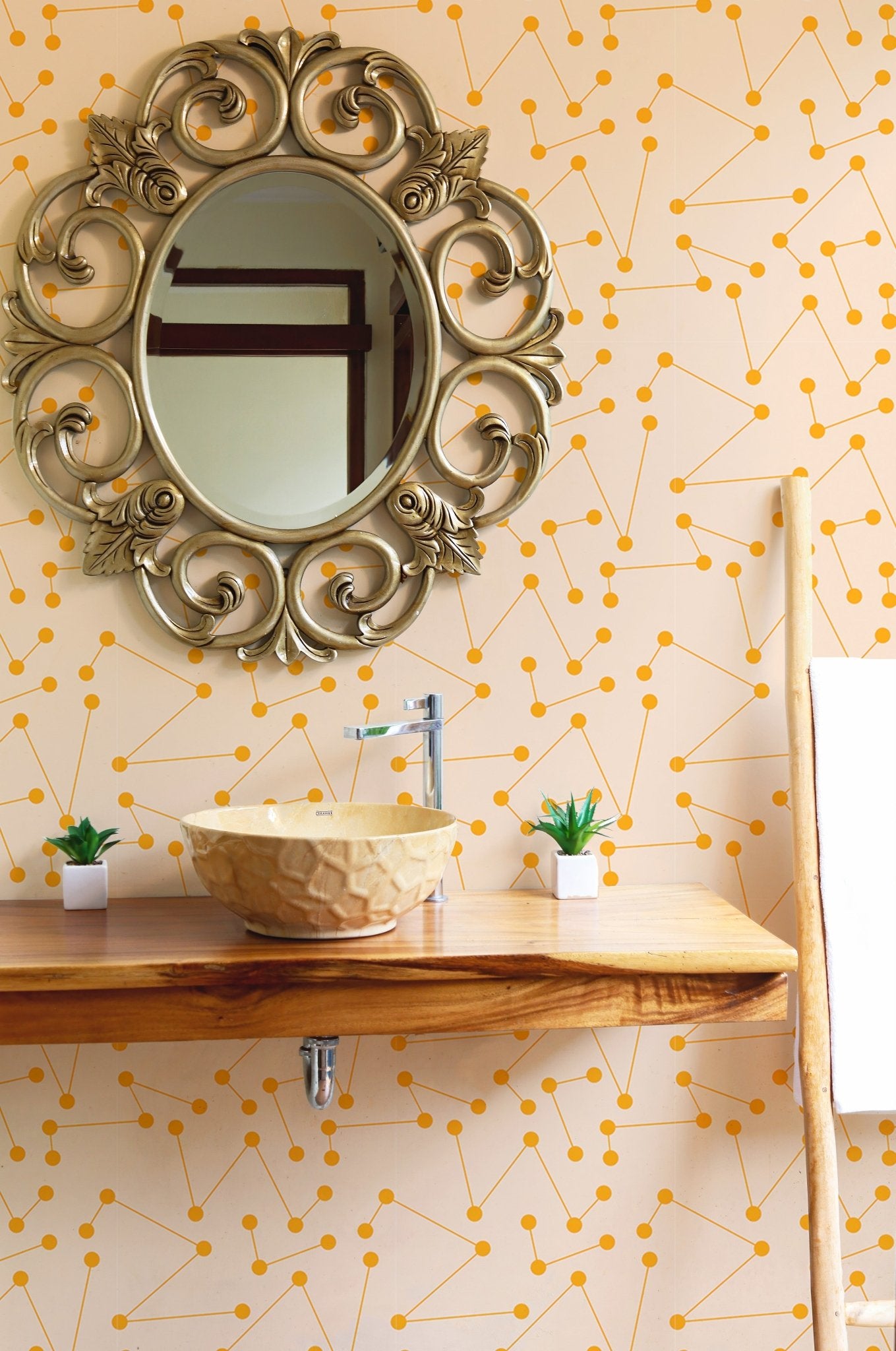 Orange shooting star wall mural in a bathroom behind a round gold mirror.