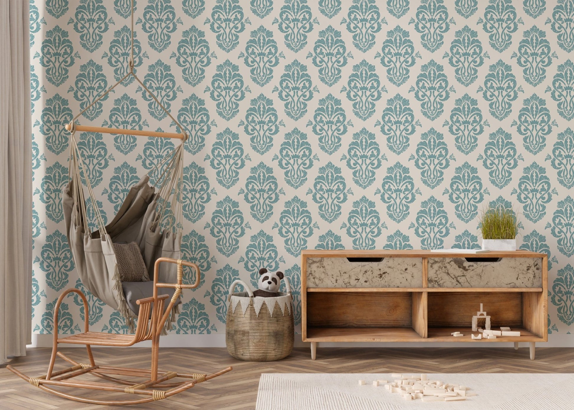 Teal damask wallpaper in a nursery area with a rocking chair and wooden cabinet.